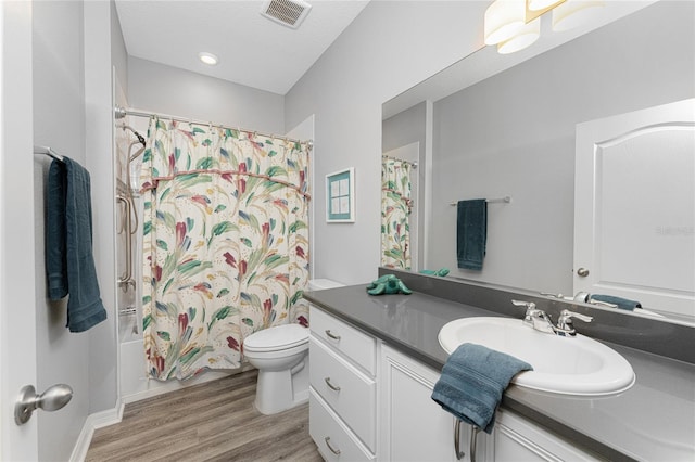 full bathroom featuring shower / tub combo with curtain, hardwood / wood-style flooring, vanity, a textured ceiling, and toilet