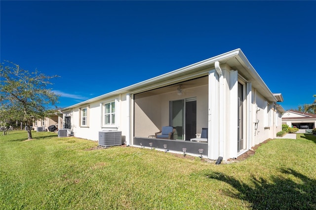 back of house with ceiling fan, central AC unit, and a lawn