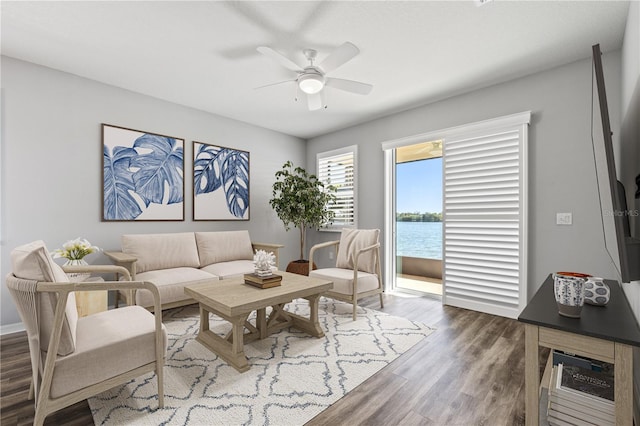 living room with a water view, ceiling fan, and dark hardwood / wood-style flooring