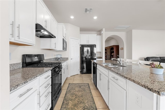 kitchen featuring sink, white cabinets, an island with sink, light tile patterned flooring, and black appliances