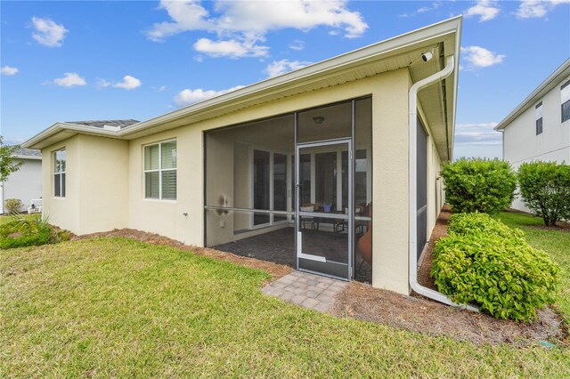 rear view of property with a yard and a sunroom