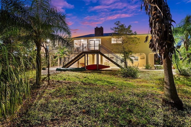 8625 SW County Road 769, Arcadia, FL 34269 - back of property at dusk featuring stairway, a chimney, stucco siding, and a yard