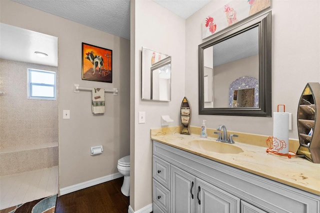 bathroom featuring vanity, hardwood / wood-style flooring, a textured ceiling, and toilet