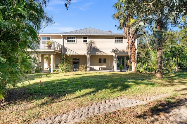 rear view of house with a yard and a balcony