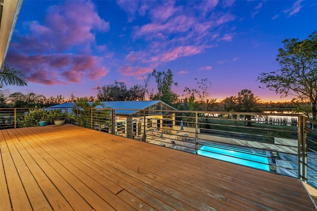 deck at dusk featuring a swimming pool