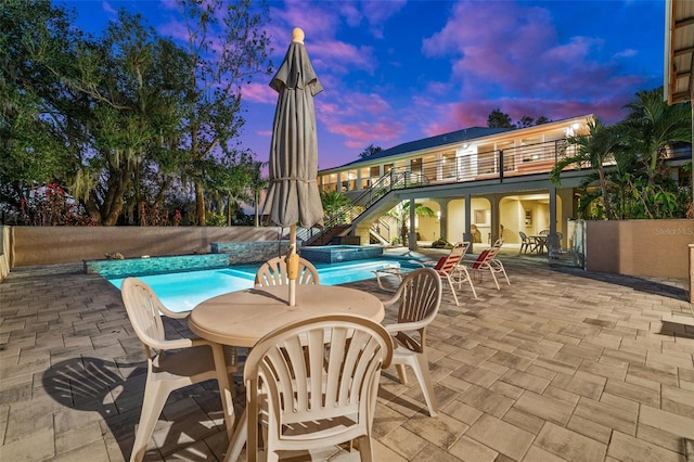 pool at dusk with a patio area