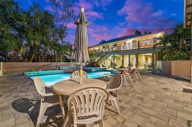 8625 SW County Road 769, Arcadia, FL 34269 - pool at dusk featuring stairs, outdoor dining area, a patio, and a pool with connected hot tub