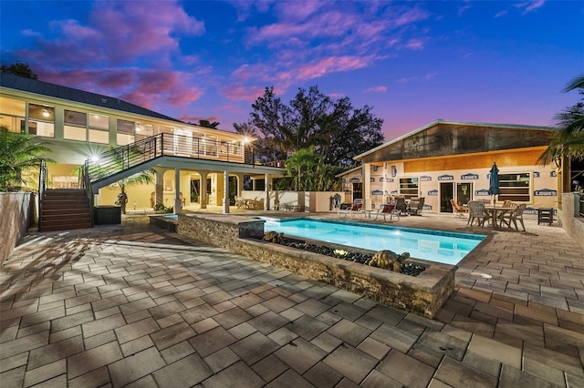 pool at dusk featuring a patio area