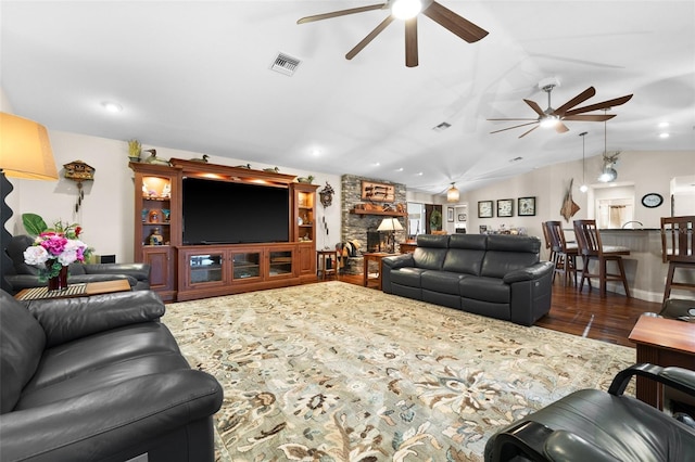 living room featuring lofted ceiling, dark hardwood / wood-style flooring, a fireplace, and ceiling fan