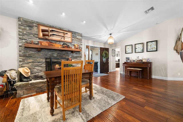 dining room featuring vaulted ceiling, dark hardwood / wood-style floors, and a fireplace