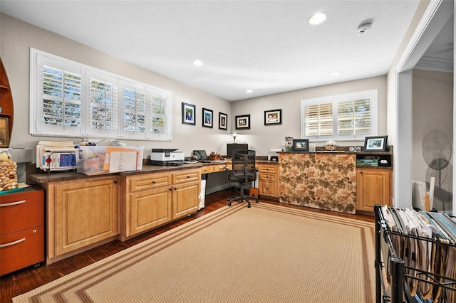 home office with plenty of natural light, dark wood-type flooring, and built in desk