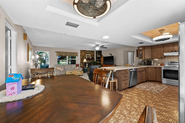 dining space featuring sink, ceiling fan, and a tray ceiling