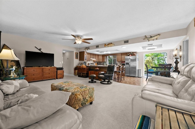 carpeted living room with a textured ceiling and ceiling fan