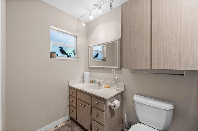 bathroom featuring vanity, toilet, a textured ceiling, and rail lighting