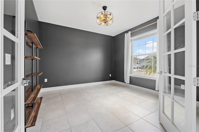 spare room with french doors, light tile patterned flooring, and a chandelier