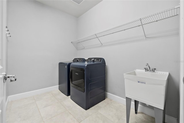 clothes washing area with light tile patterned flooring, independent washer and dryer, and sink