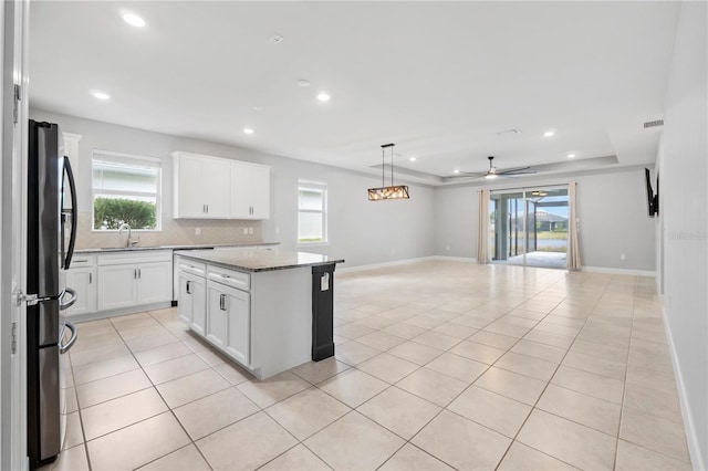 kitchen featuring stainless steel fridge, a kitchen island, plenty of natural light, and ceiling fan