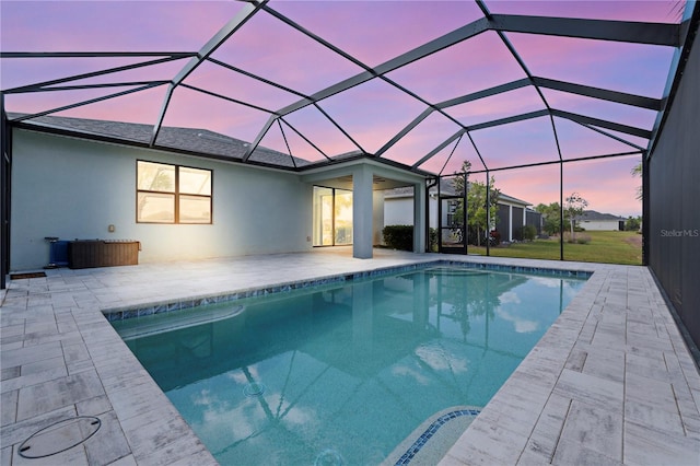 pool at dusk with a patio and glass enclosure