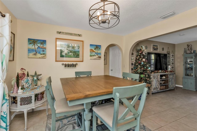 tiled dining space featuring a textured ceiling and a notable chandelier