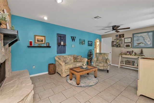 living room featuring ceiling fan, a fireplace, and light tile patterned flooring