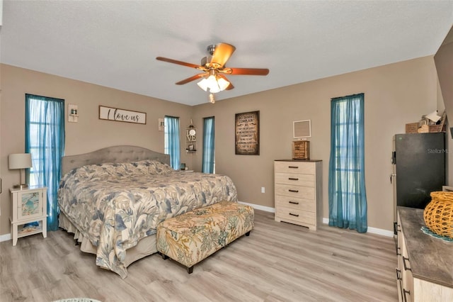 bedroom with ceiling fan, a textured ceiling, and light wood-type flooring