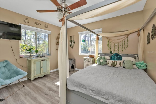 bedroom with ceiling fan, light hardwood / wood-style flooring, and multiple windows