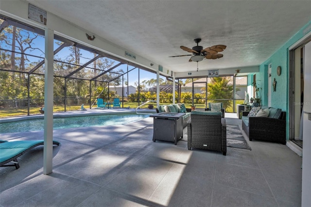 view of pool featuring a patio area, ceiling fan, an outdoor living space with a fire pit, and glass enclosure