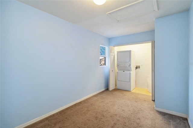 carpeted empty room featuring stacked washing maching and dryer