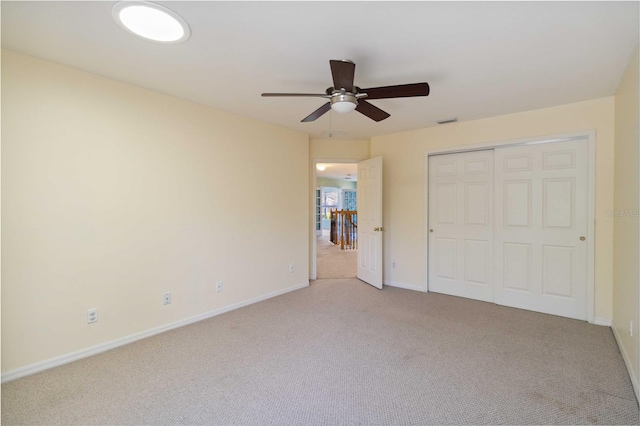 unfurnished bedroom featuring ceiling fan, light carpet, and a closet