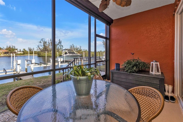 sunroom with a water view and ceiling fan