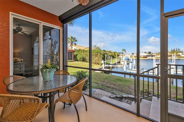 sunroom / solarium with ceiling fan, a water view, and a wealth of natural light