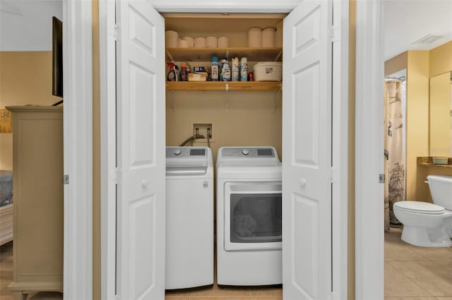 clothes washing area featuring light tile patterned flooring and washer and dryer