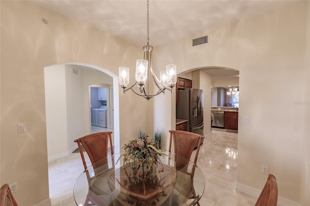 dining area with separate washer and dryer and a notable chandelier