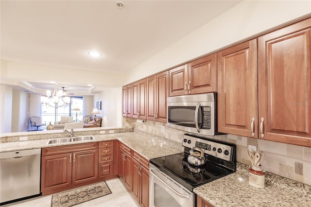 kitchen featuring an inviting chandelier, sink, appliances with stainless steel finishes, tasteful backsplash, and light stone counters