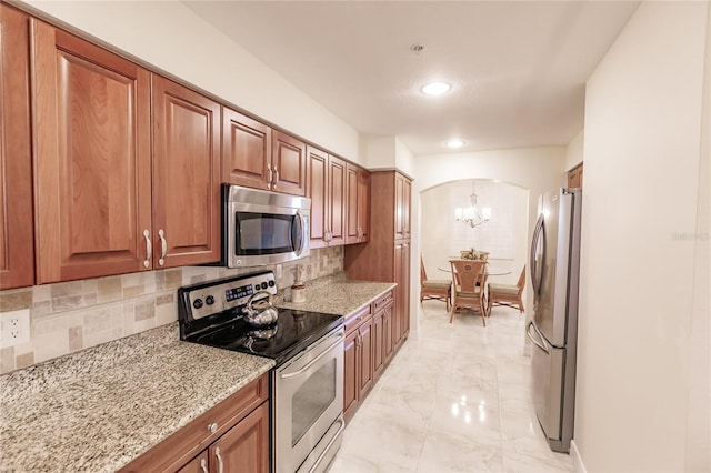 kitchen with a chandelier, backsplash, stainless steel appliances, and light stone counters