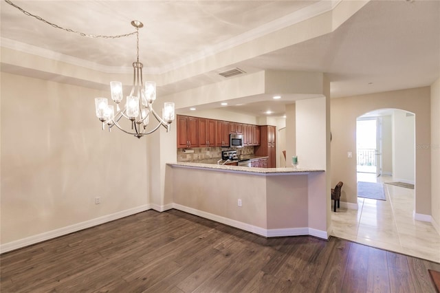 kitchen featuring kitchen peninsula, tasteful backsplash, ornamental molding, stainless steel appliances, and hardwood / wood-style floors