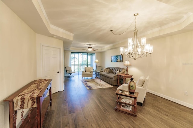 living room with ceiling fan with notable chandelier, crown molding, dark wood-type flooring, and a tray ceiling