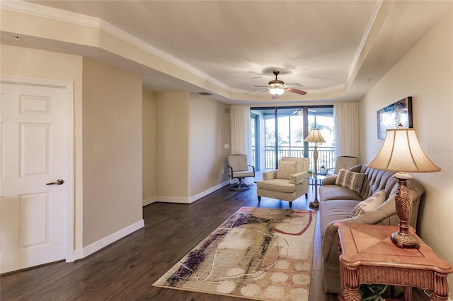 living room featuring a tray ceiling, ceiling fan, dark hardwood / wood-style floors, and ornamental molding