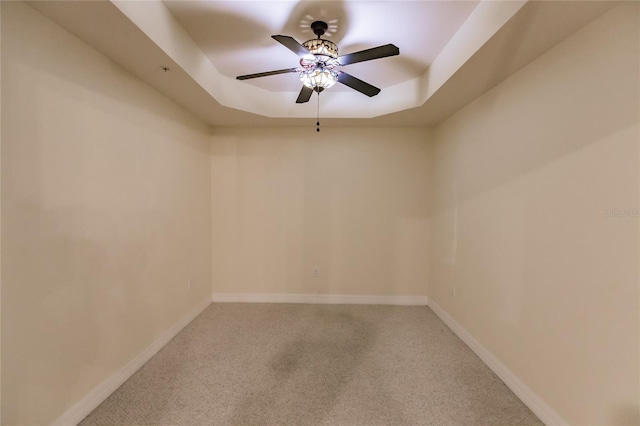 empty room featuring a tray ceiling, ceiling fan, and carpet flooring