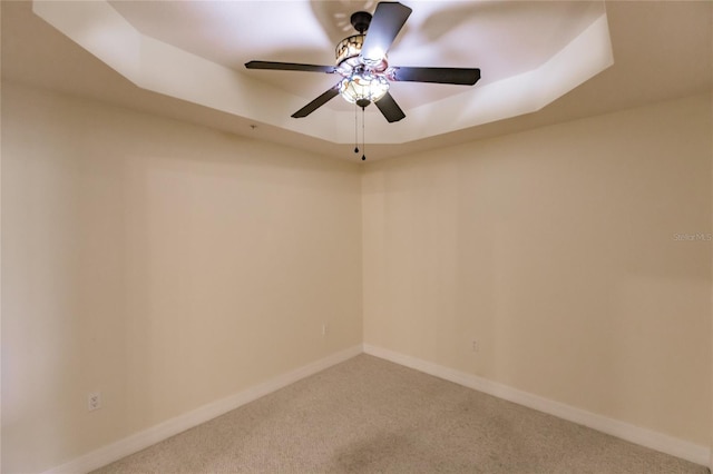 spare room featuring a tray ceiling, ceiling fan, and carpet flooring