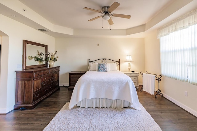 bedroom with dark hardwood / wood-style flooring, a raised ceiling, and ceiling fan