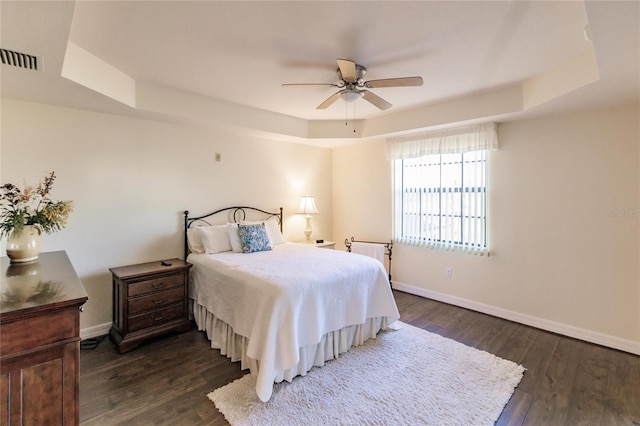 bedroom featuring ceiling fan, a raised ceiling, and dark wood-type flooring