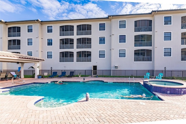 view of pool with a community hot tub, pool water feature, and a patio area