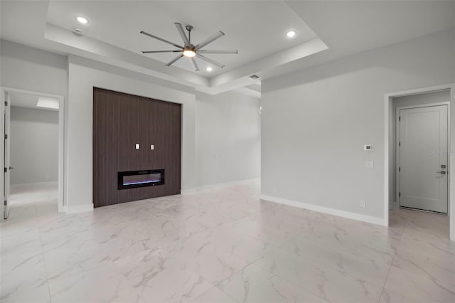 unfurnished living room with a raised ceiling and ceiling fan