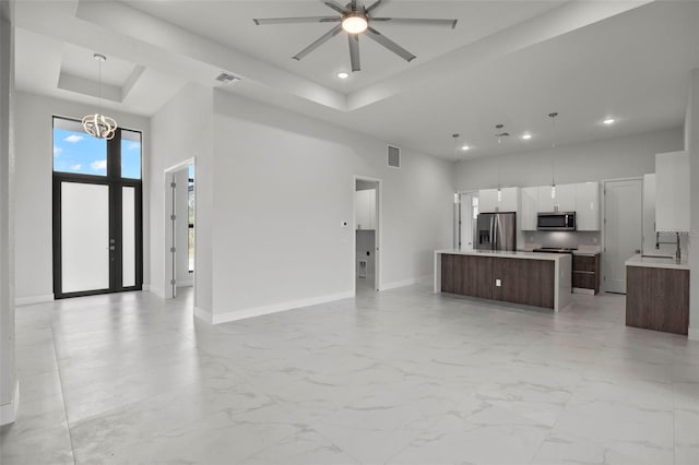 kitchen featuring dark brown cabinets, ceiling fan with notable chandelier, stainless steel appliances, a center island, and hanging light fixtures