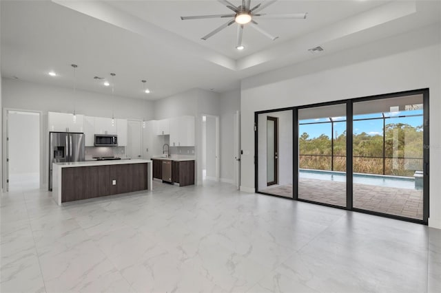 kitchen featuring appliances with stainless steel finishes, dark brown cabinetry, a kitchen island, white cabinetry, and hanging light fixtures