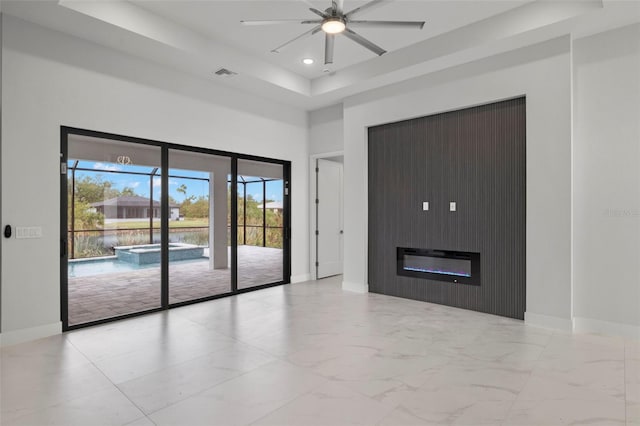 unfurnished living room with ceiling fan, a towering ceiling, and a tray ceiling