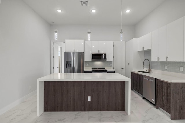 kitchen with decorative light fixtures, a kitchen island, sink, and stainless steel appliances