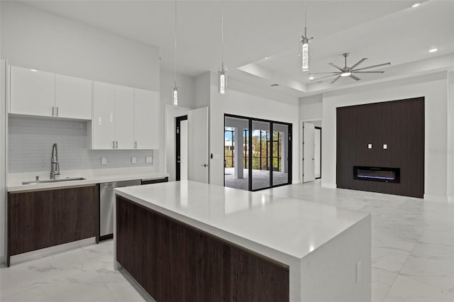 kitchen with pendant lighting, sink, ceiling fan, a kitchen island, and white cabinetry