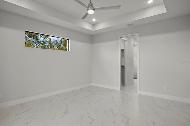 spare room with ceiling fan and a raised ceiling